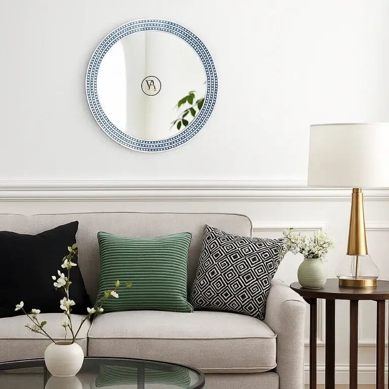 Living room with a bone inlay round blue mirror, sofa with decorative pillows, and side table with lamp.