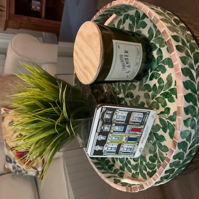 Decorative round inlay tray with candle, plant, and coaster on wooden table