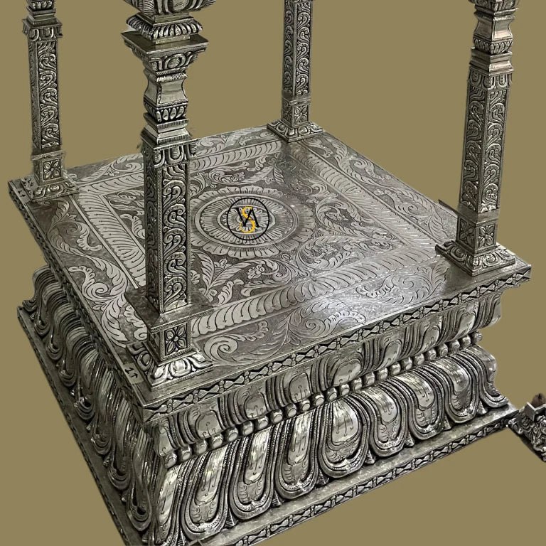 Beautifully carved white metal temple base with floral and peacock patterns.