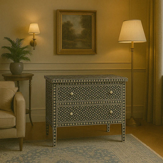 A black and white geometric patterned 2-drawer chest with bone inlay details, placed in a room with a lamp, painting, and plant in the background.