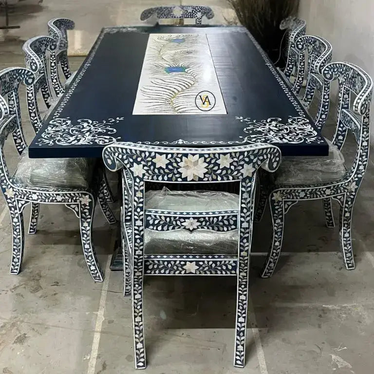 Decorative bone inlay dining table with white patterns surrounded by matching chairs on a marble floor.