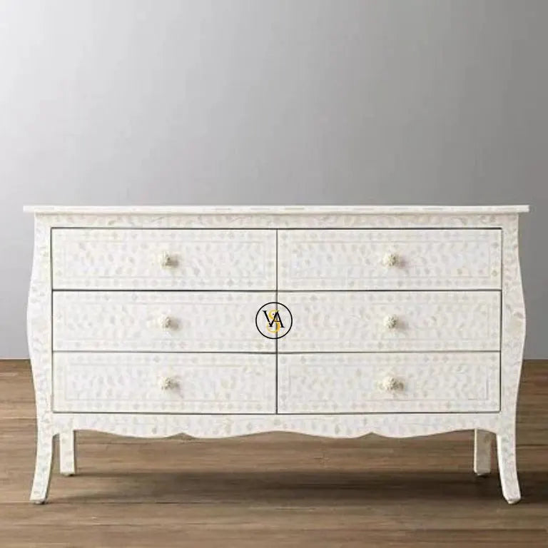 White dresser with decorative pattern on a gray wall background