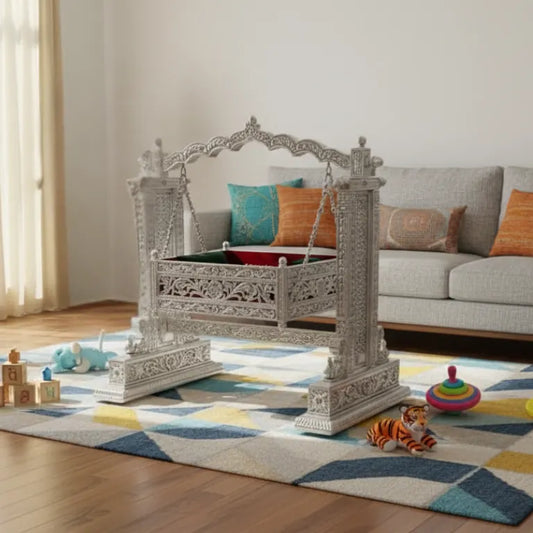 Handcrafted Silver Baby Cradle with Intricate Design in a room with a sofa and toys on a geometric rug.