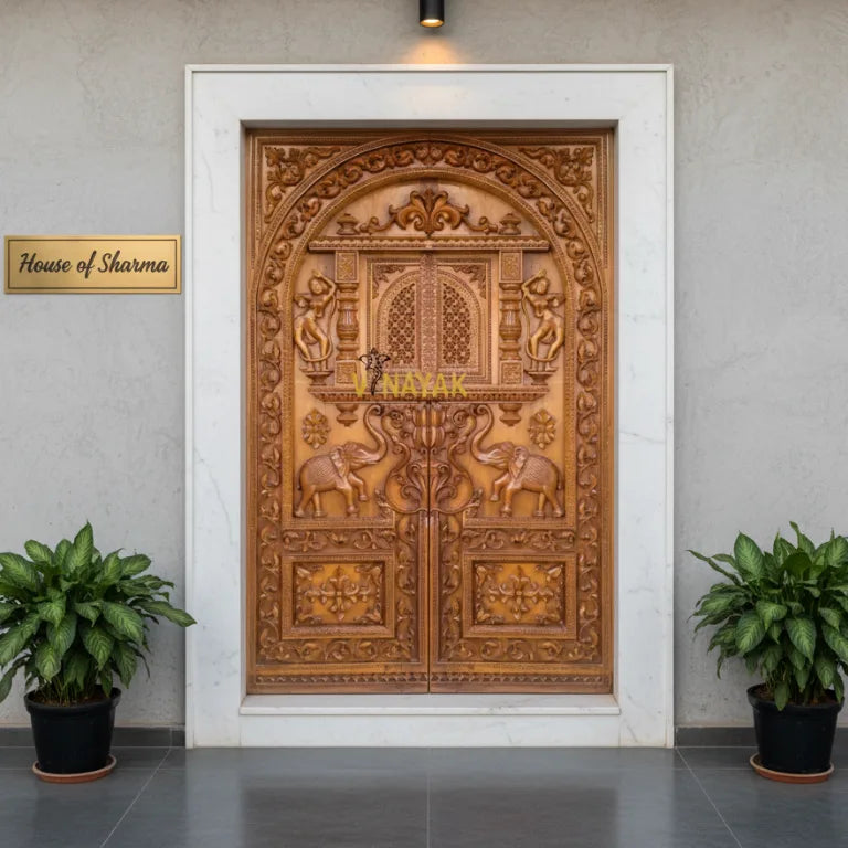 Handcrafted wooden carving door with intricate carvings in a room with plants and a sign reading 'House of Sharma'.