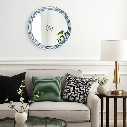 Living room with a bone inlay round blue mirror, sofa with decorative pillows, and side table with lamp.