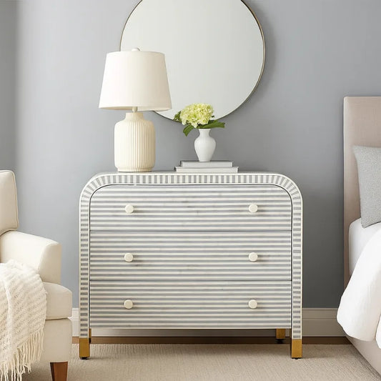 Luxury Bone Inlay Waterfall Bedroom Dresser in Gray placed in modern bedroom with lamp, books and round wall mirror.