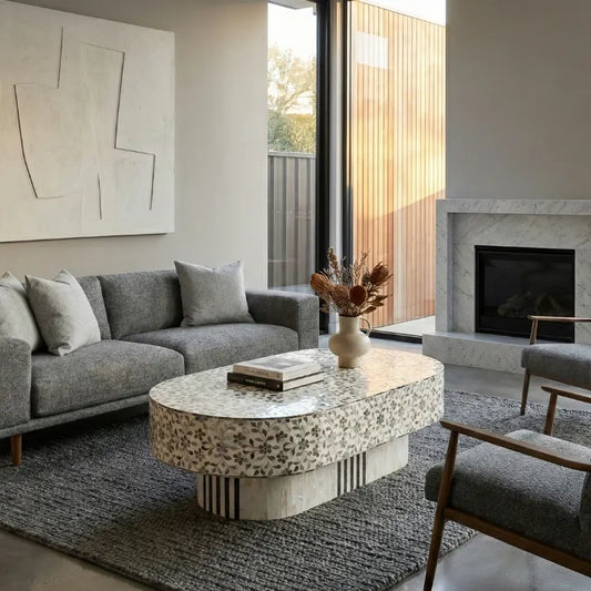 Luxury Oval Shape Coffee Table in Mother of Pearl – Living Room Setup with gray sofa and abstract art on wall.