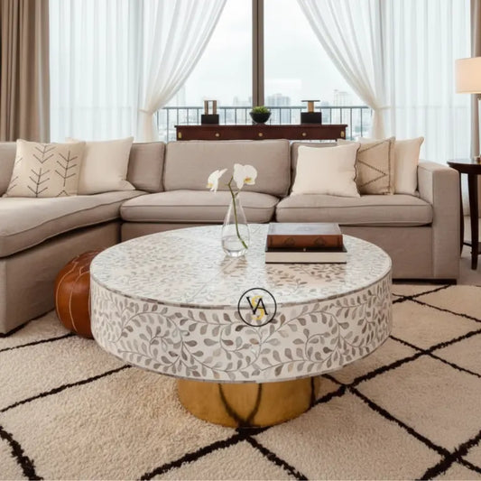 Mother of Pearl White Round Coffee Table placed in Living room with a beige sectional sofa and decorative coffee table.